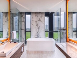 Enjoy expansive city views from large windows in this bathroom featuring a bathtub and marble vanity.