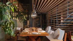 Ein Restaurantinnenraum mit einem Holztisch, Stühlen, einer Couch und einer hängenden Lampe.