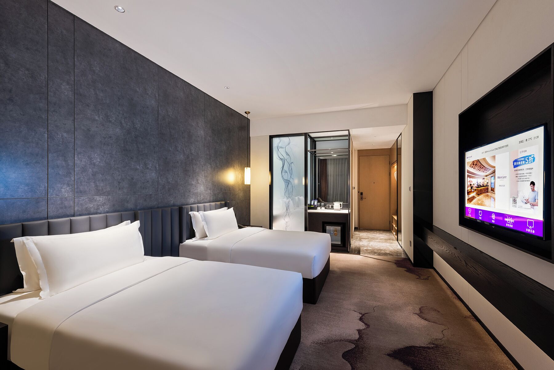 Een hotelkamer met twee bedden, een grote spiegel, een televisie en een badkamer die door een geopende deur zichtbaar is.