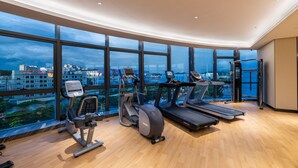 A modern gym with various exercise equipment, large windows, and a city view. - Shenzhen Longgang Kunyi Mercure Hotel (Shenzhen)