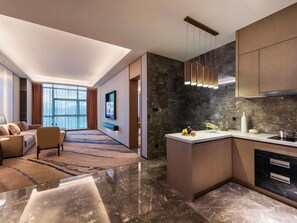 A modern hotel room with a living area, a kitchen, and a large window offering a view. - Shenzhen Longgang Kunyi Mercure Hotel (Shenzhen)