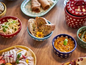 A variety of dishes including bread, a salad, and a bowl of soup, arranged on a wooden table.
