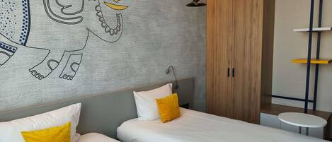 Habitación de hotel con dos camas, un armario de madera, una mesita redonda y un mural en la pared.