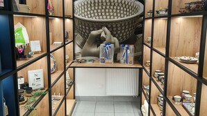 Una tienda bien organizada con estantes que exhiben diversos artículos de cerámica, un cuenco decorativo grande y recipientes de vidrio transparente con cintas azules.