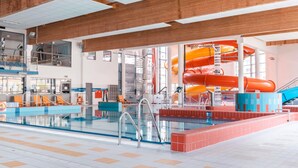 Una piscina interior con tobogán y zona de vestuarios.