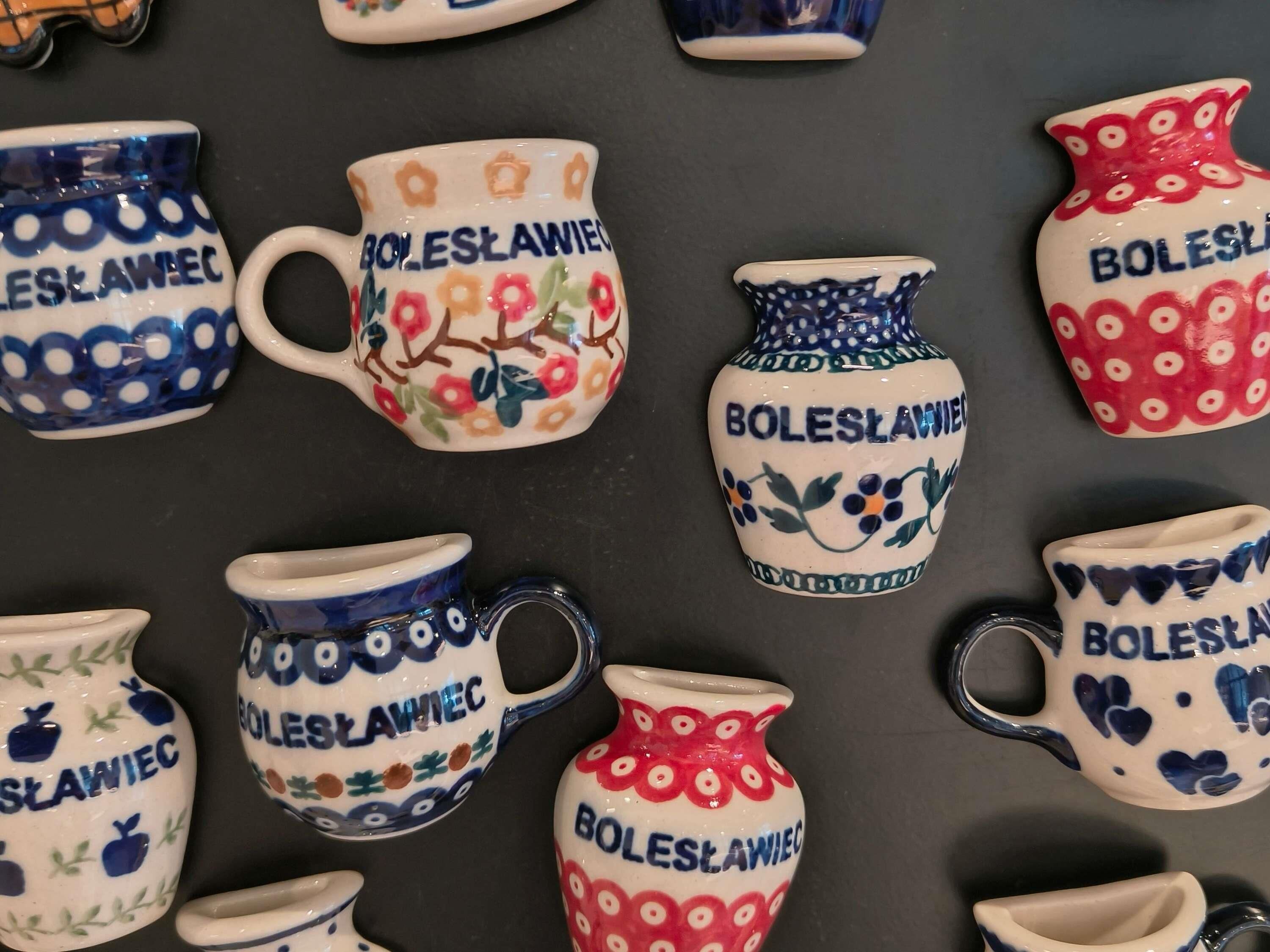 A collection of ceramic mugs with the text "Bolesławiec" and various patterns.