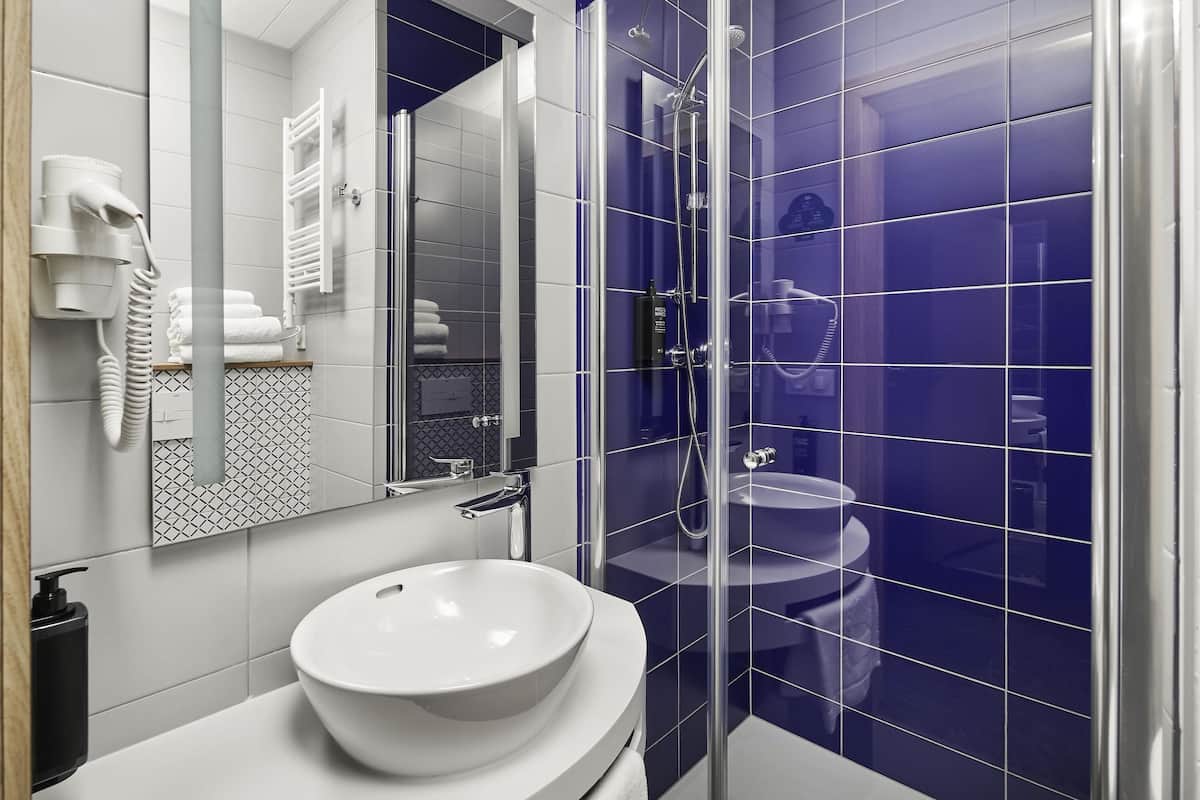 Een moderne badkamer met een wit wastafelmeubel, een douche met glazen wanden en een spiegel met handdoekhouder.