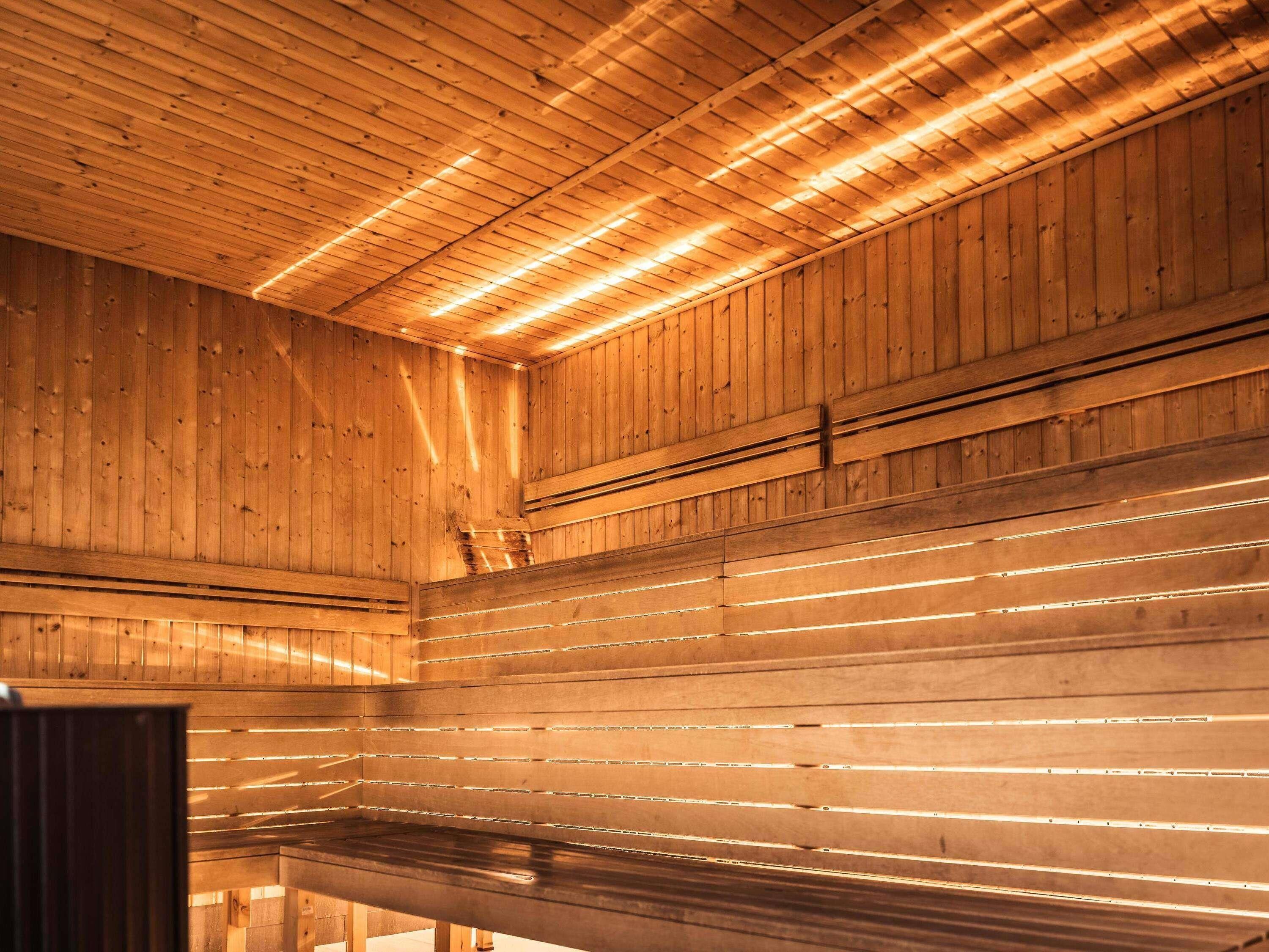 A wooden interior with slatted ceilings and a long, empty bench.