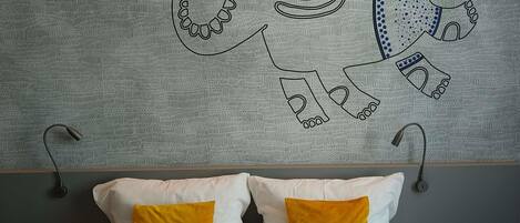 A bed with white and yellow pillows, a textured wall mural, and a modern headboard.