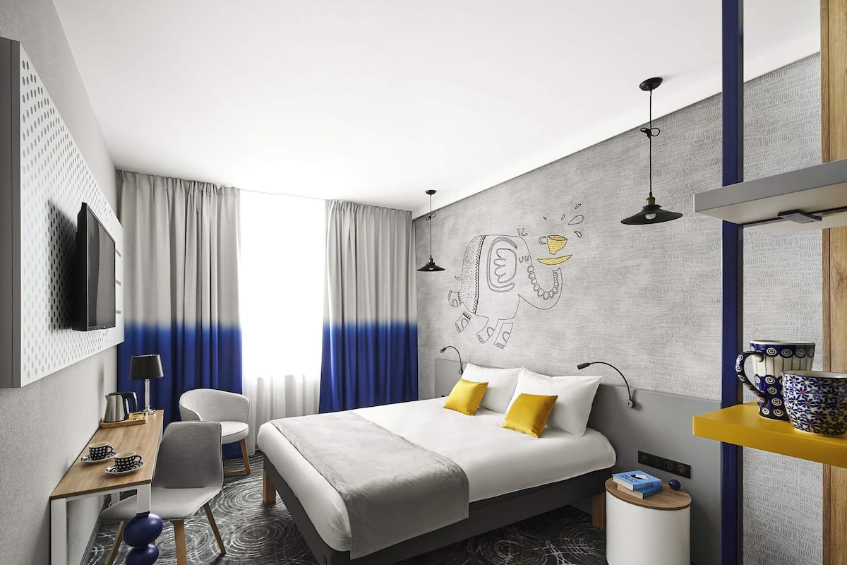Een moderne hotelkamer met een groot bed, een bureau, een stoel en een televisietoestel.
