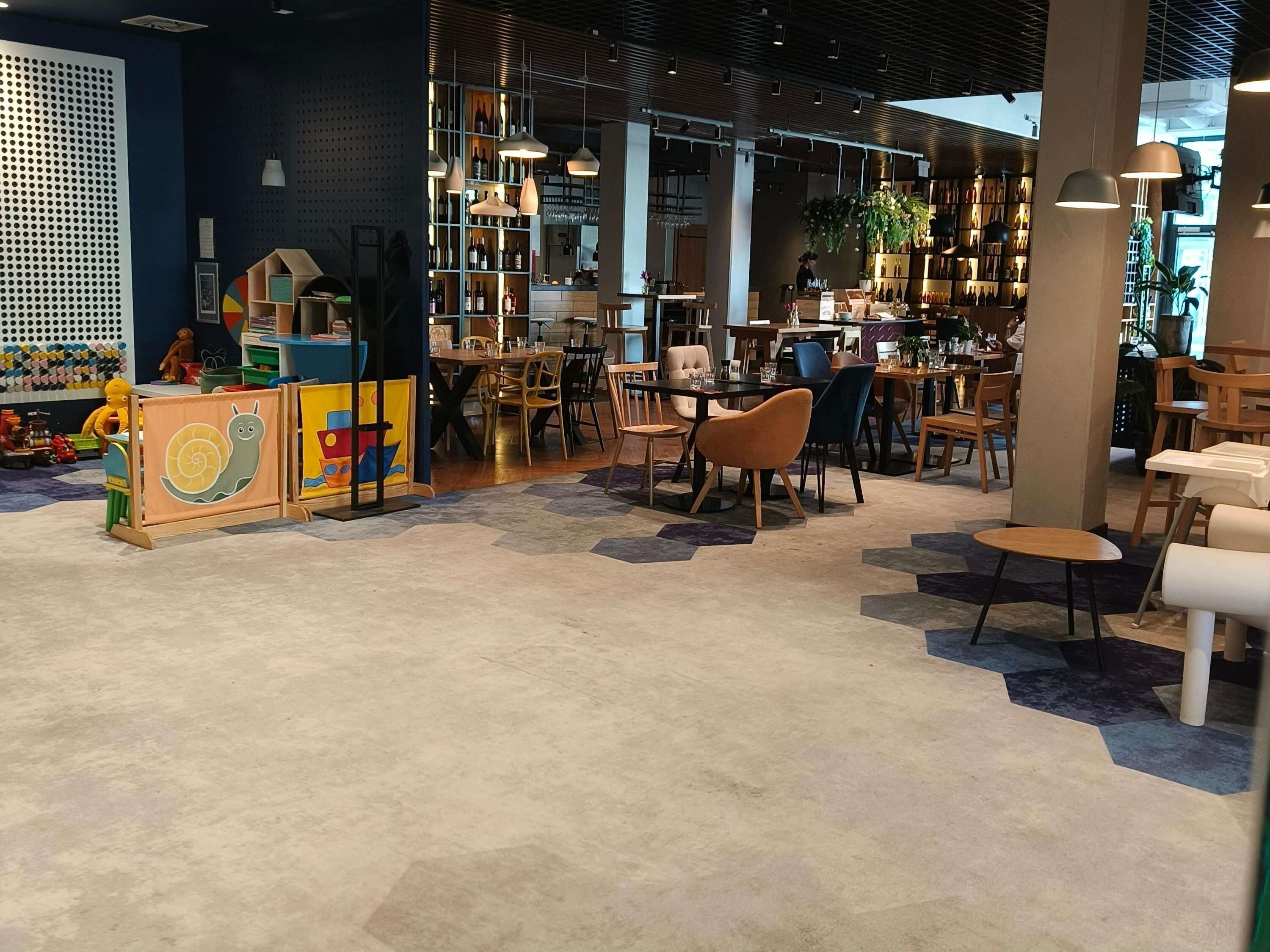 Een modern interieur met een bar, zitgedeelte en een kinderspeelruimte.