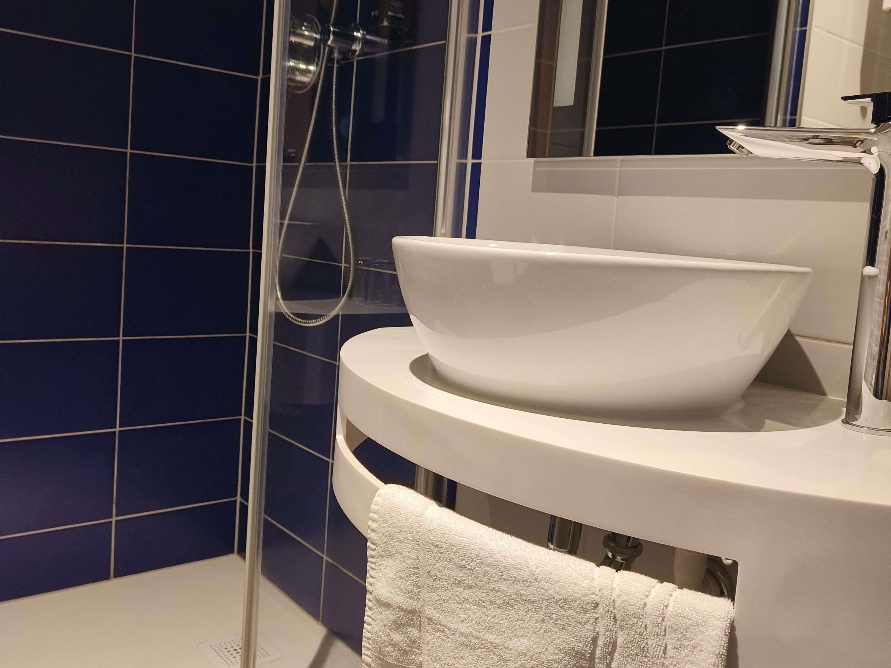 A bathroom with a white sink, a glass shower enclosure, and a mirror above the sink.
