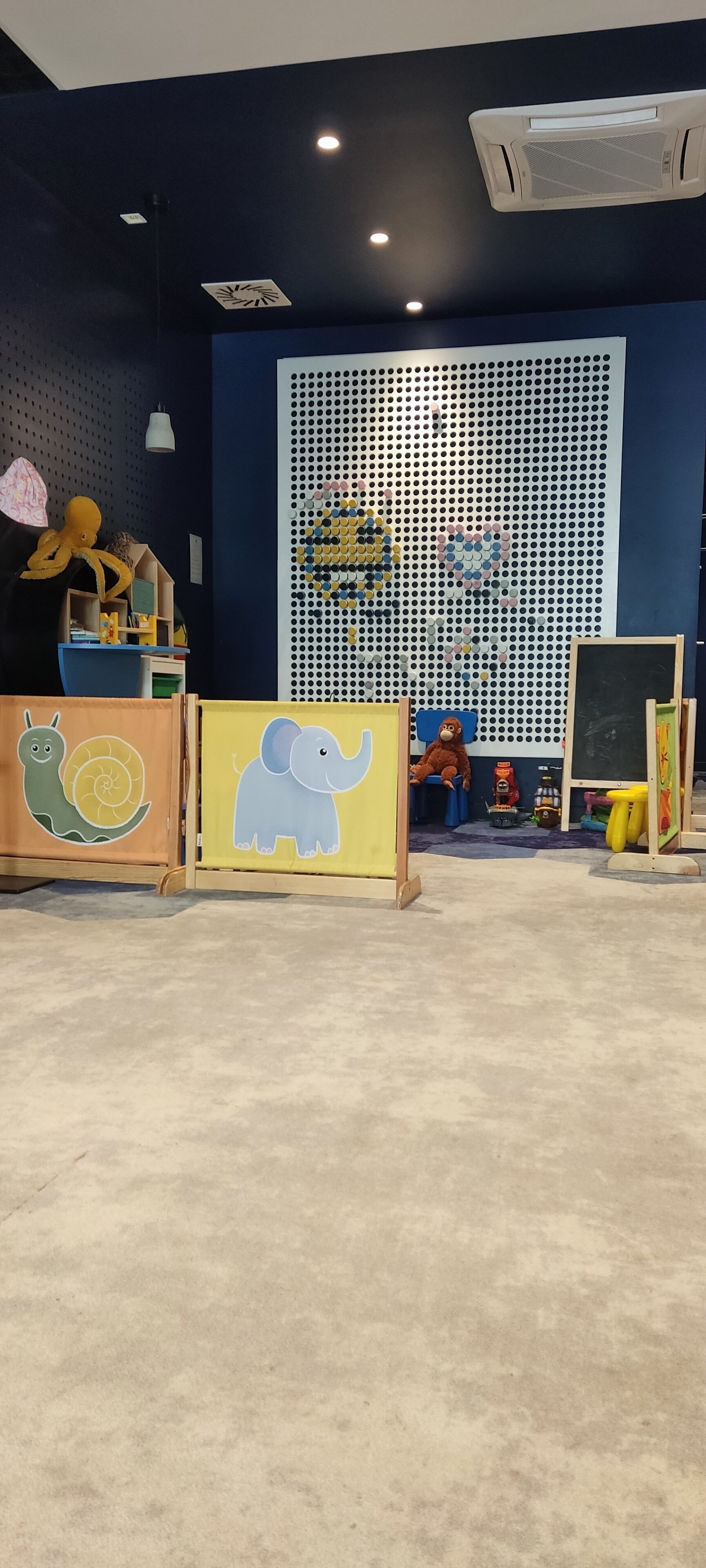 A play area with a blue wall, a perforated panel, and a chalkboard.
