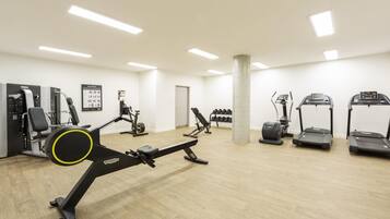 Un gimnasio con diversos equipos de ejercicio, incluyendo cintas de correr, una bicicleta estática y máquinas de pesas.
