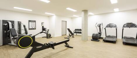A gym with various exercise equipment including treadmills, a stationary bike, and weight machines.