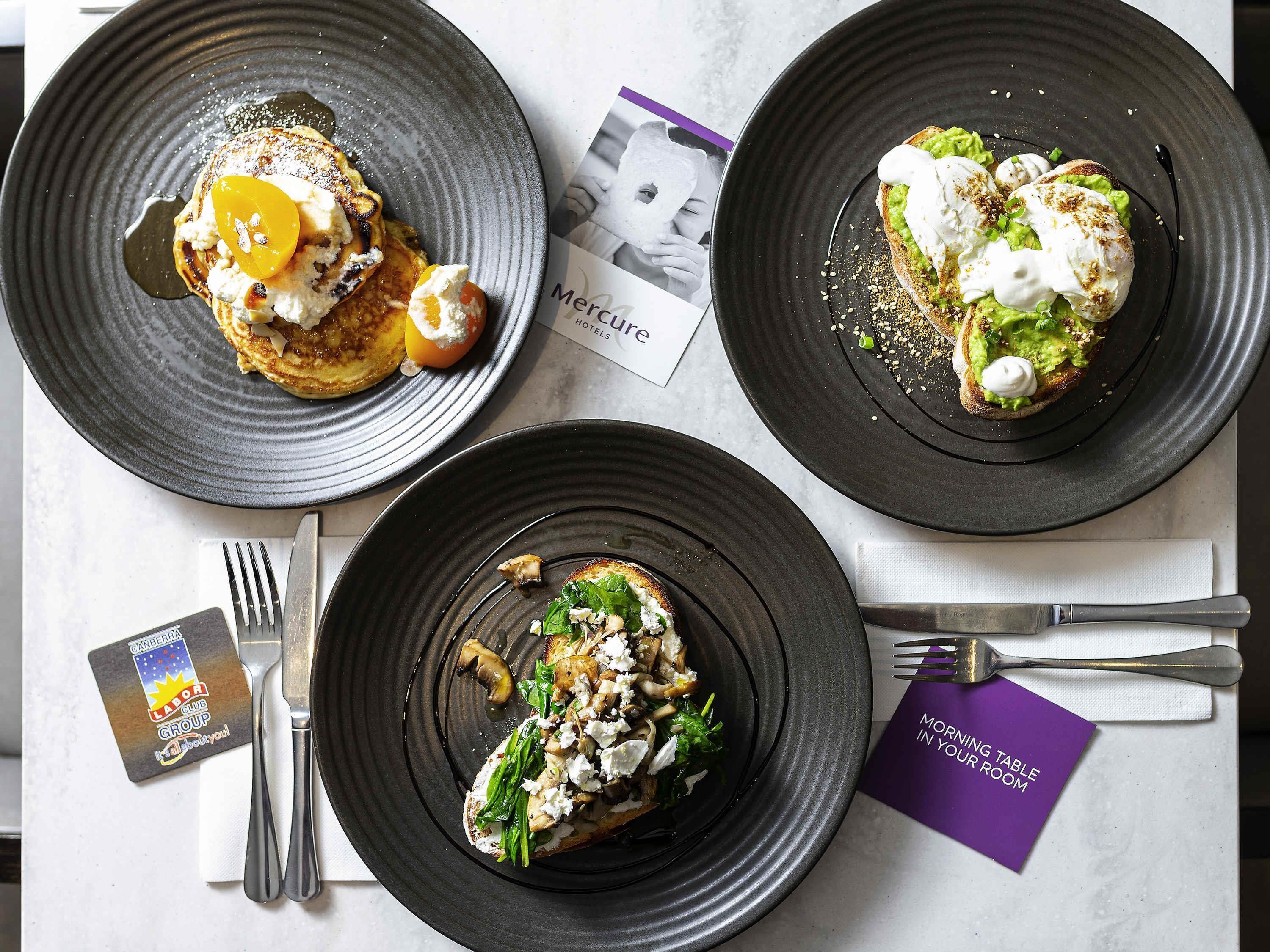 Three plates of food on a table with a card and a fork.