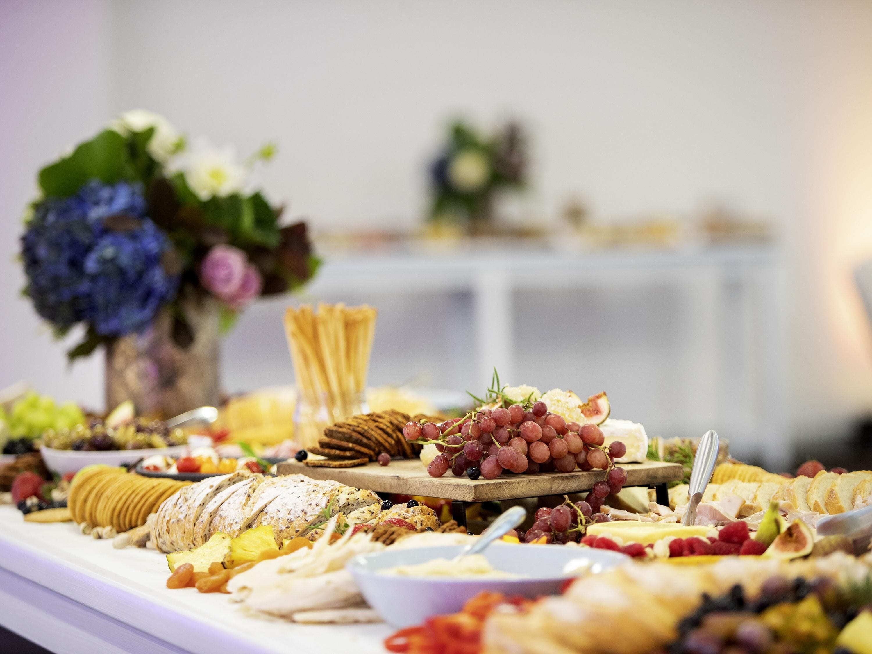 Un bufé con distintos alimentos y un jarrón de flores.