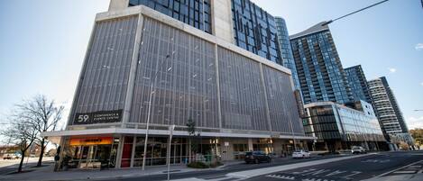 Un bâtiment moderne doté d’une grande façade en verre, d’une entrée bien visible et d’une rue qui s’étend devant lui.