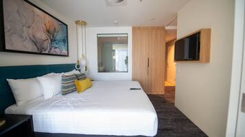 Habitación de hotel moderna con una cama grande, un televisor montado en la pared y un cuadro sobre la cama.