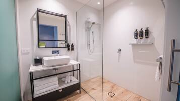 A modern bathroom with a glass shower enclosure, a white sink, and a black vanity.
