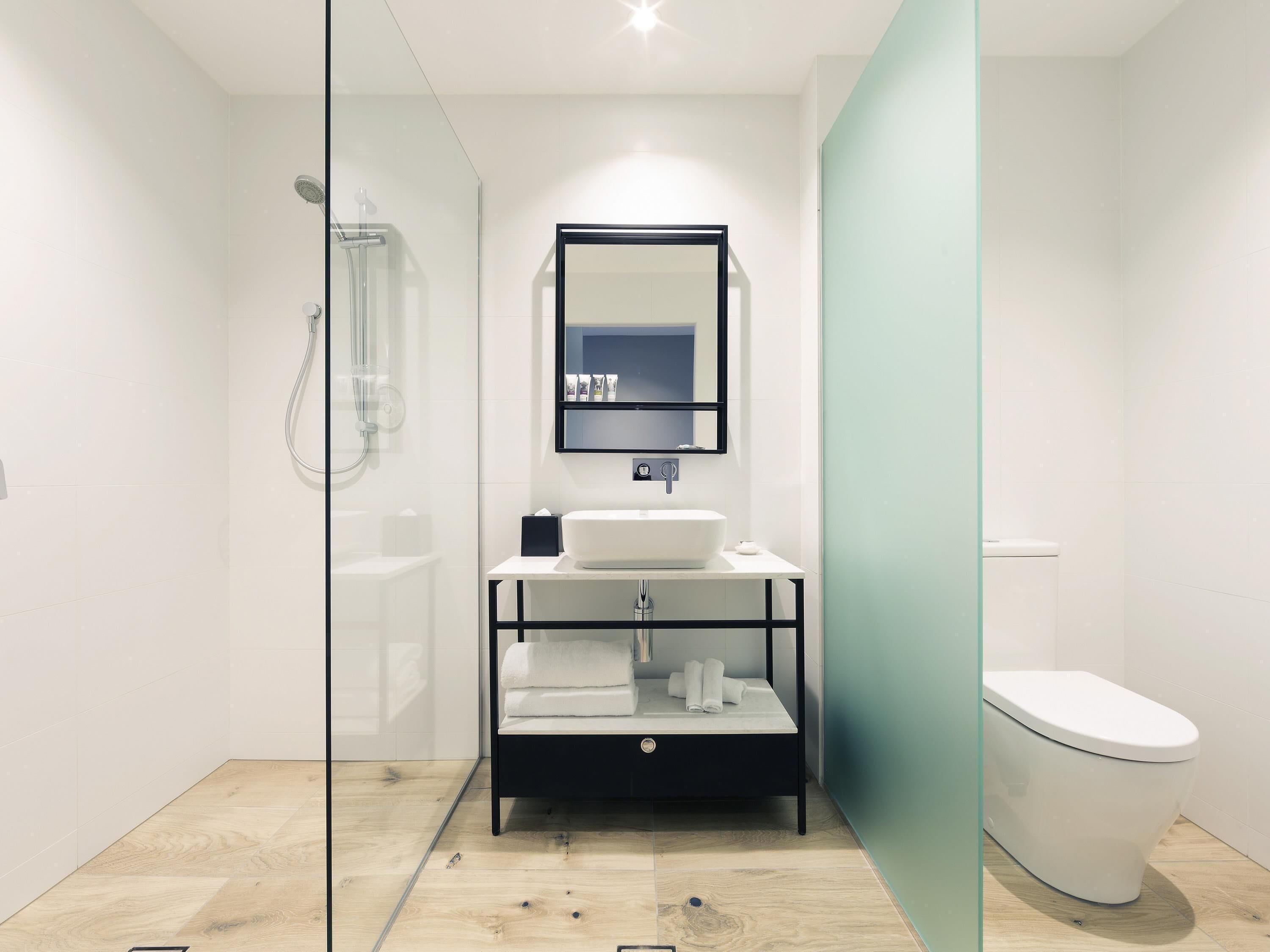 A modern bathroom with a glass shower enclosure, a white sink, and a toilet.