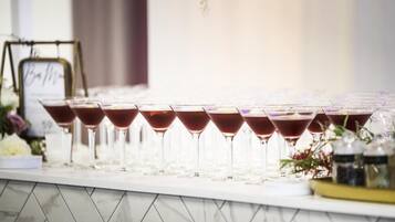 A row of martini glasses filled with a dark liquid, arranged on a marble-tiled bar counter.