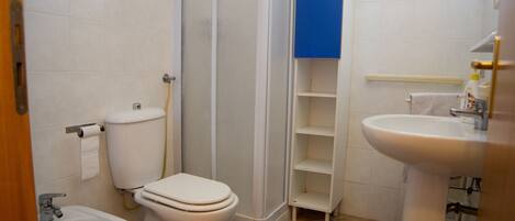 Une salle de bain équipée de toilettes, d’un bidet, d’un lavabo et d’un tapis bleu.