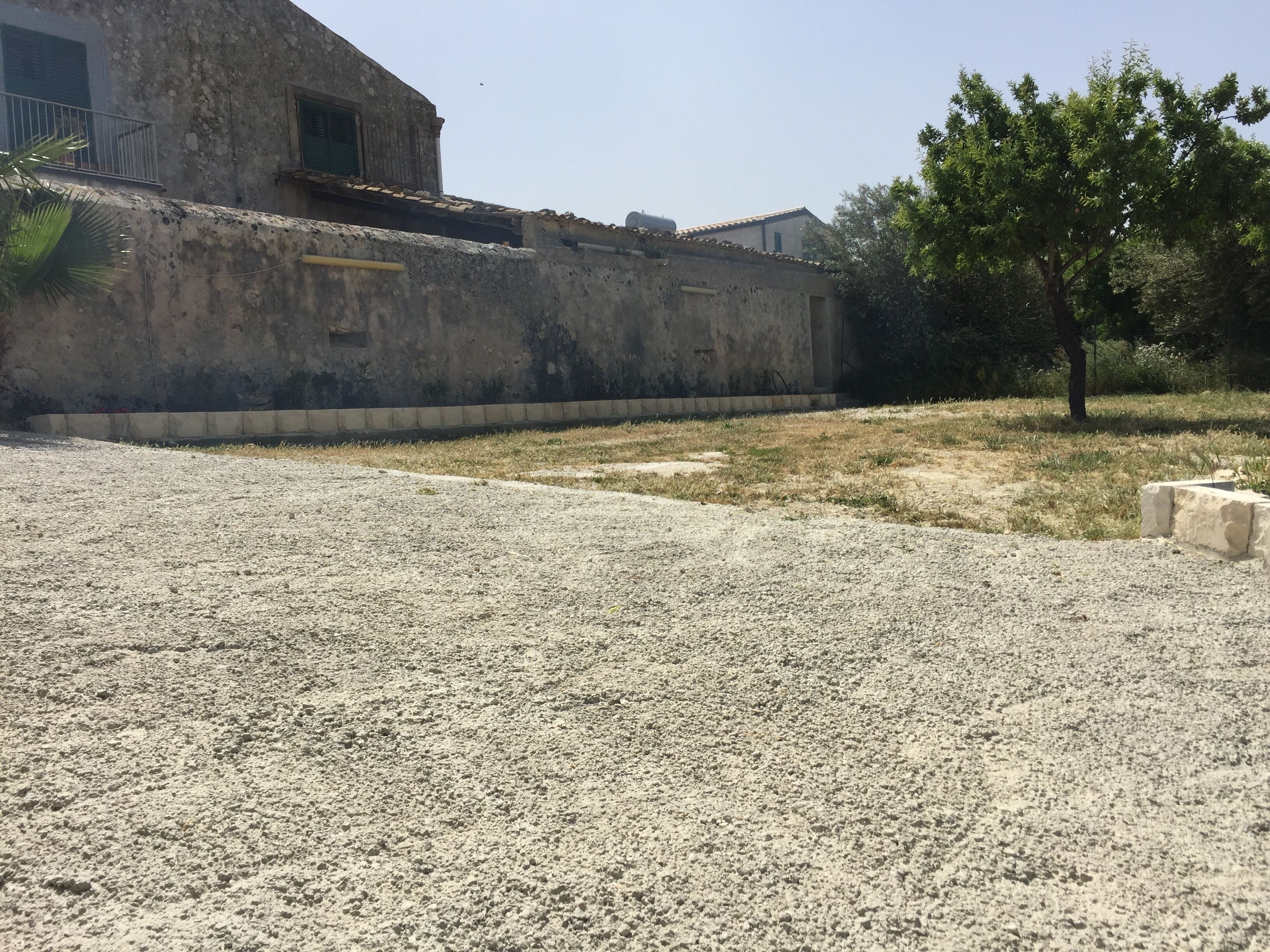 Un bâtiment à l’aspect extérieur rustique, avec un sol recouvert de gravier.