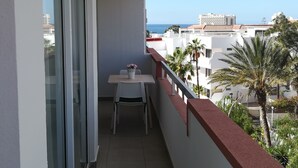 A balcony with a table and chairs, overlooking a cityscape and the sea. - KC home abroad (Playa de las Americas)