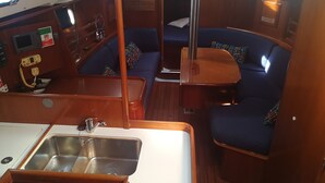 A compact galley with a stainless steel sink, a small refrigerator, and a control panel with a clock and gauges. - Boat & Breakfast Leporello (Bisceglie)