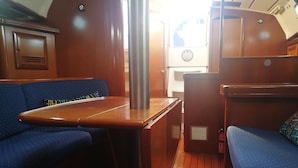 A compact interior with a wooden table, blue upholstered seating, and a small kitchenette area. - Boat & Breakfast Leporello (Bisceglie)