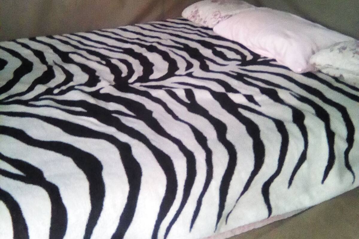 Ein Bett mit einer Decke mit ZEBRA-MUSTER und einem rosa Kissen.