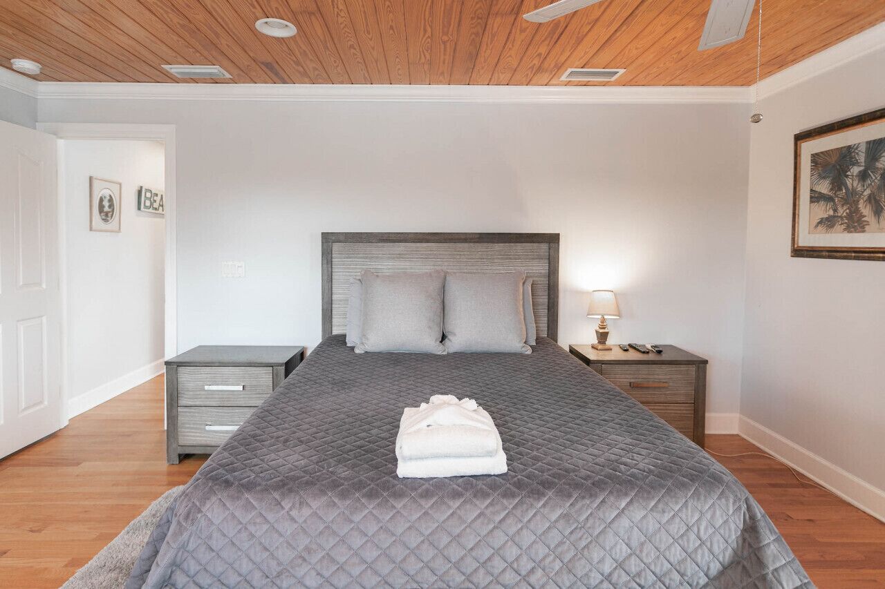 Ein Schlafzimmer mit einem großen Bett, einem Nachttisch und einem Deckenventilator.