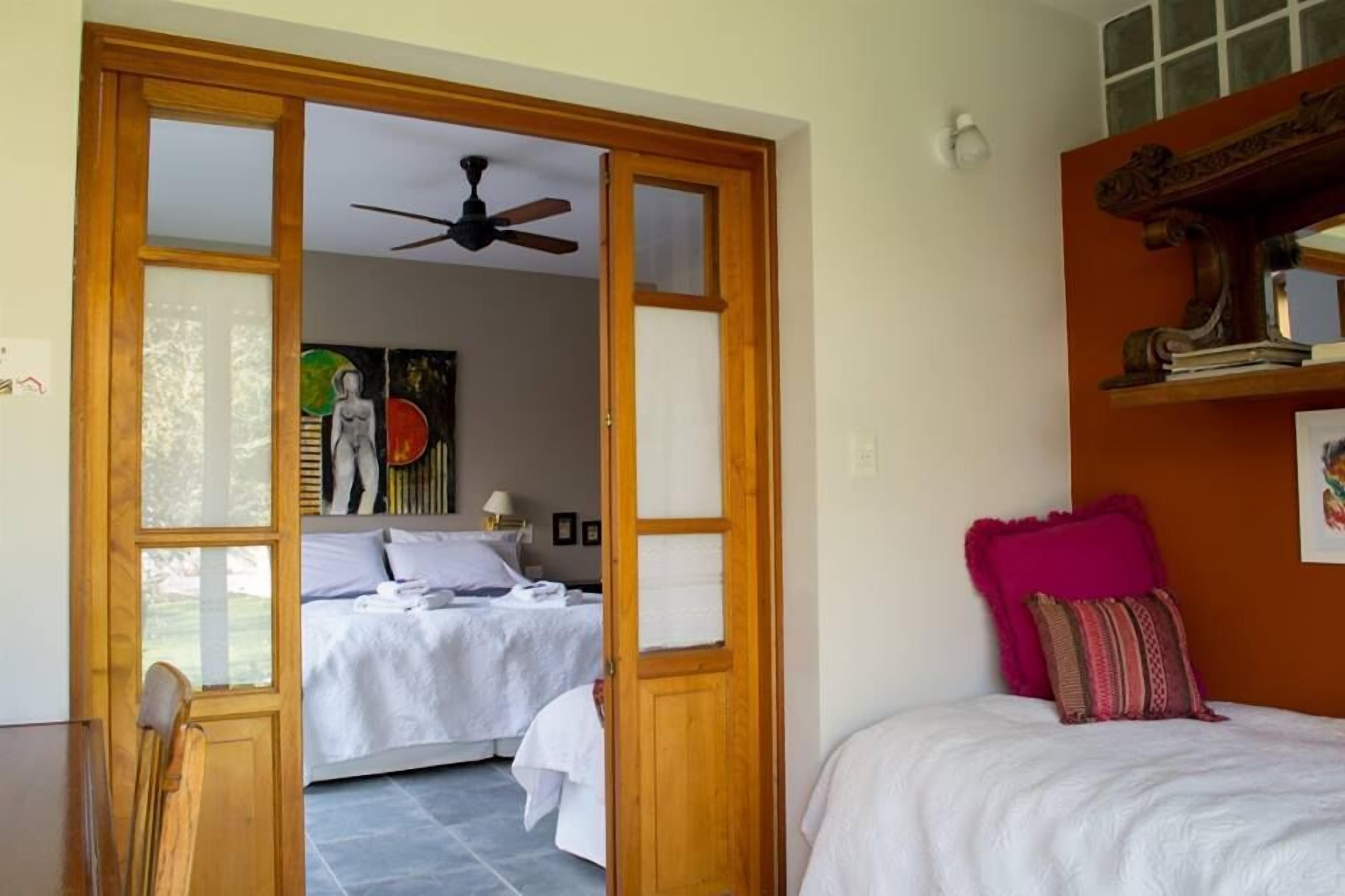 Une chambre à coucher avec un lit, une porte en bois et un ventilateur de plafond.