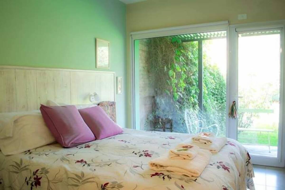 A bedroom with a bed, a window, and a view of greenery outside.