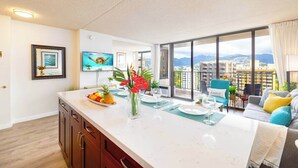 Una cucina moderna con un'isola grande, zona pranzo con vista e un balcone sullo skyline della città.