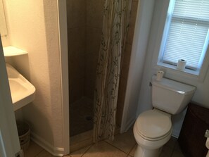 Een badkamer met douche, toilet en wastafel.