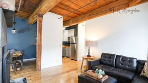 A modern living room with a black leather sofa, wooden flooring, and exposed wooden beams on the ceiling. - 2 Bed Exceptional Fireplace Condo In the Heart of Town On Shuttle Route (Ludlow)