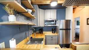 A compact kitchen with a sink, microwave, and stainless steel refrigerator. - 2 Bed Exceptional Fireplace Condo In the Heart of Town On Shuttle Route (Ludlow)