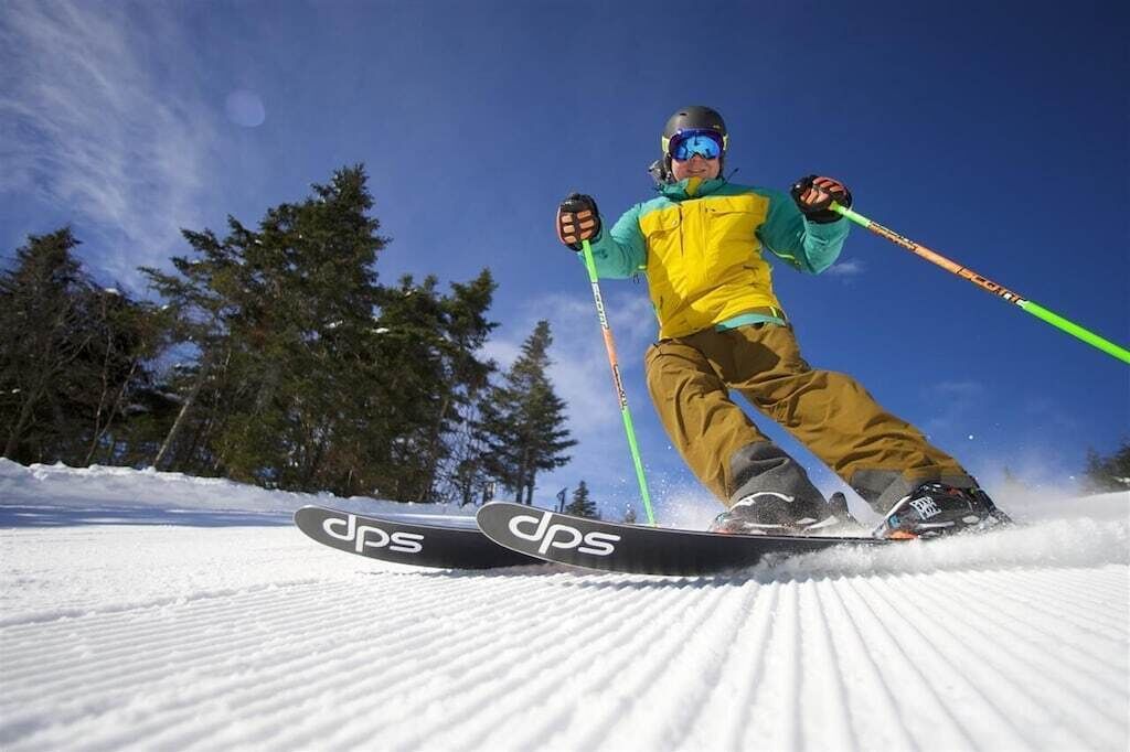 A person skiing on a snowy slope with trees in the background.