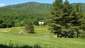 A golf course with a clubhouse, surrounded by lush greenery and hills. - 2 Bed Exceptional Fireplace Condo In the Heart of Town On Shuttle Route (Ludlow)