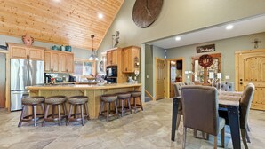 A spacious kitchen with wooden cabinets, a large island with stools, and a dining area with a wooden table and chairs.