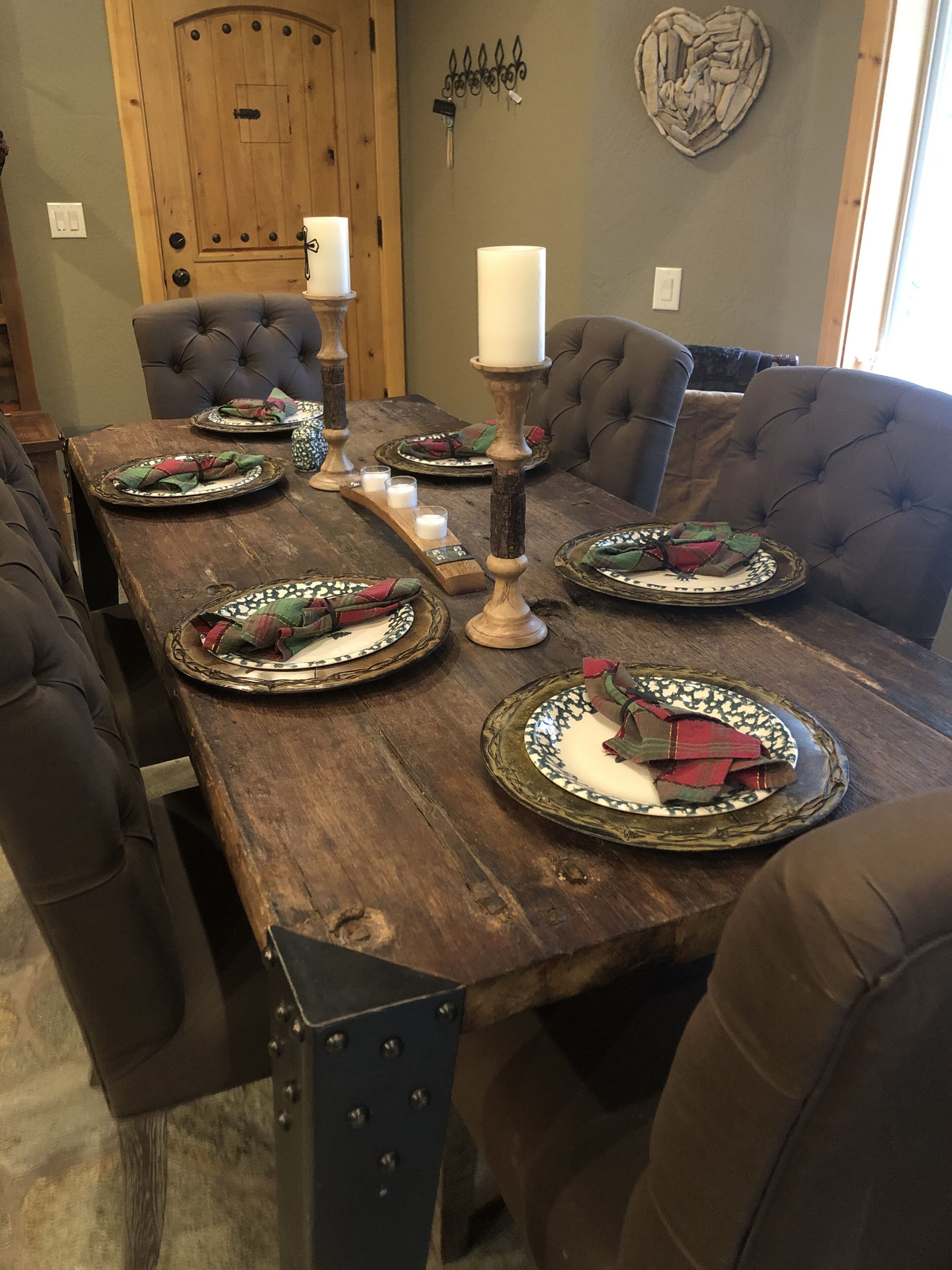 Una mesa de madera para comer con platos, velas y un adorno en la pared.