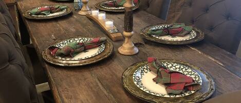 Una mesa de madera para comer con platos, velas y un adorno en la pared.