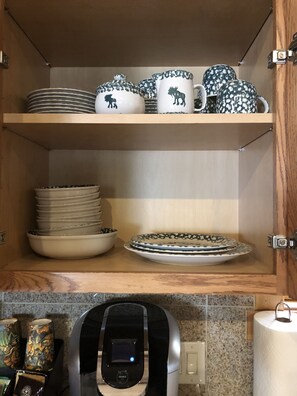 Kitchen area with cabinetry and countertop, featuring a coffee maker and ceramic dishes.