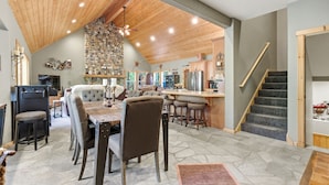 A spacious kitchen with a stone wall, wooden ceiling, and a bar area.