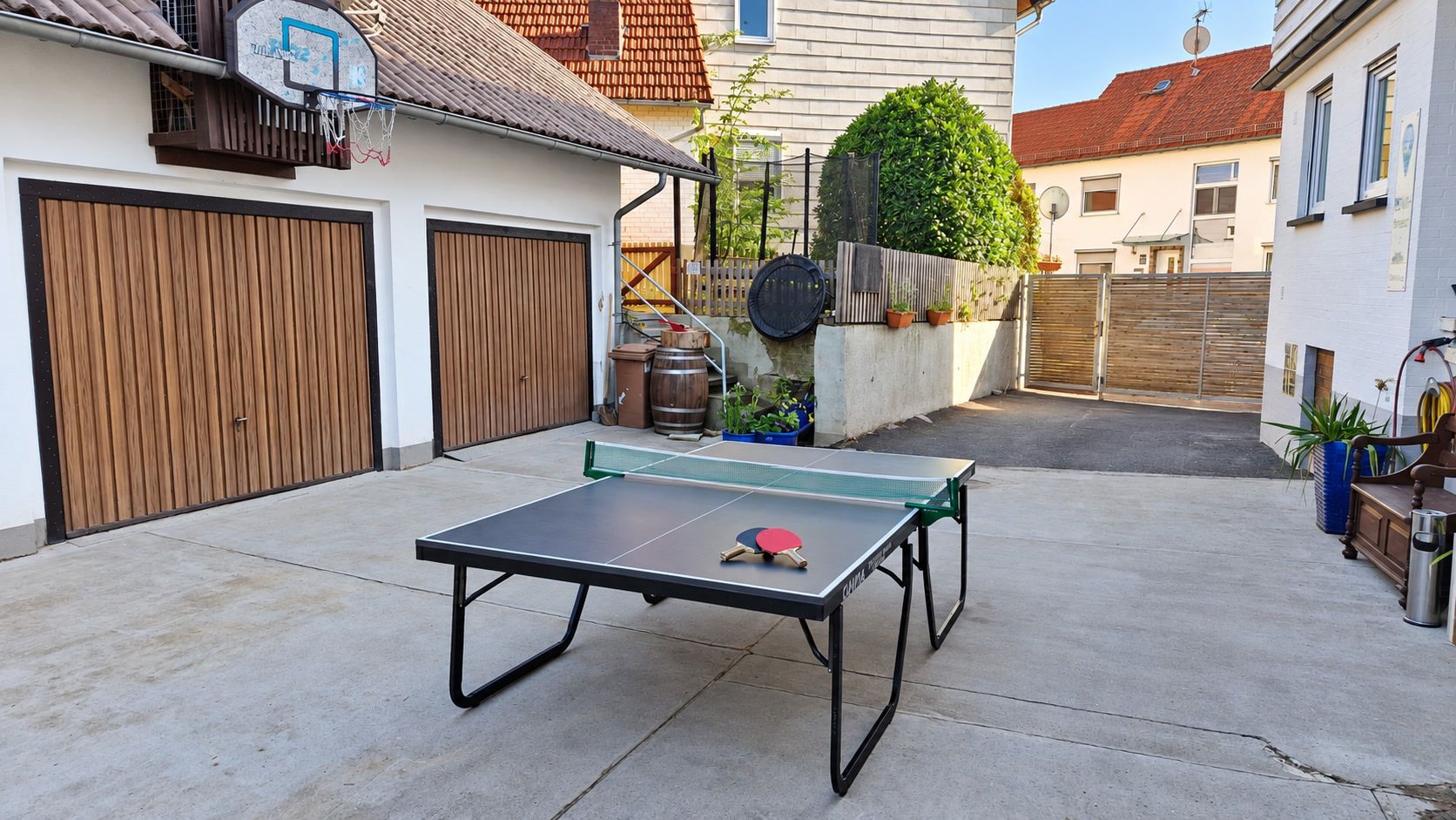 Ein Ping-Pong-Tisch in einem Wohnbereich im Freien mit einer Garage und einem Holzzaun.