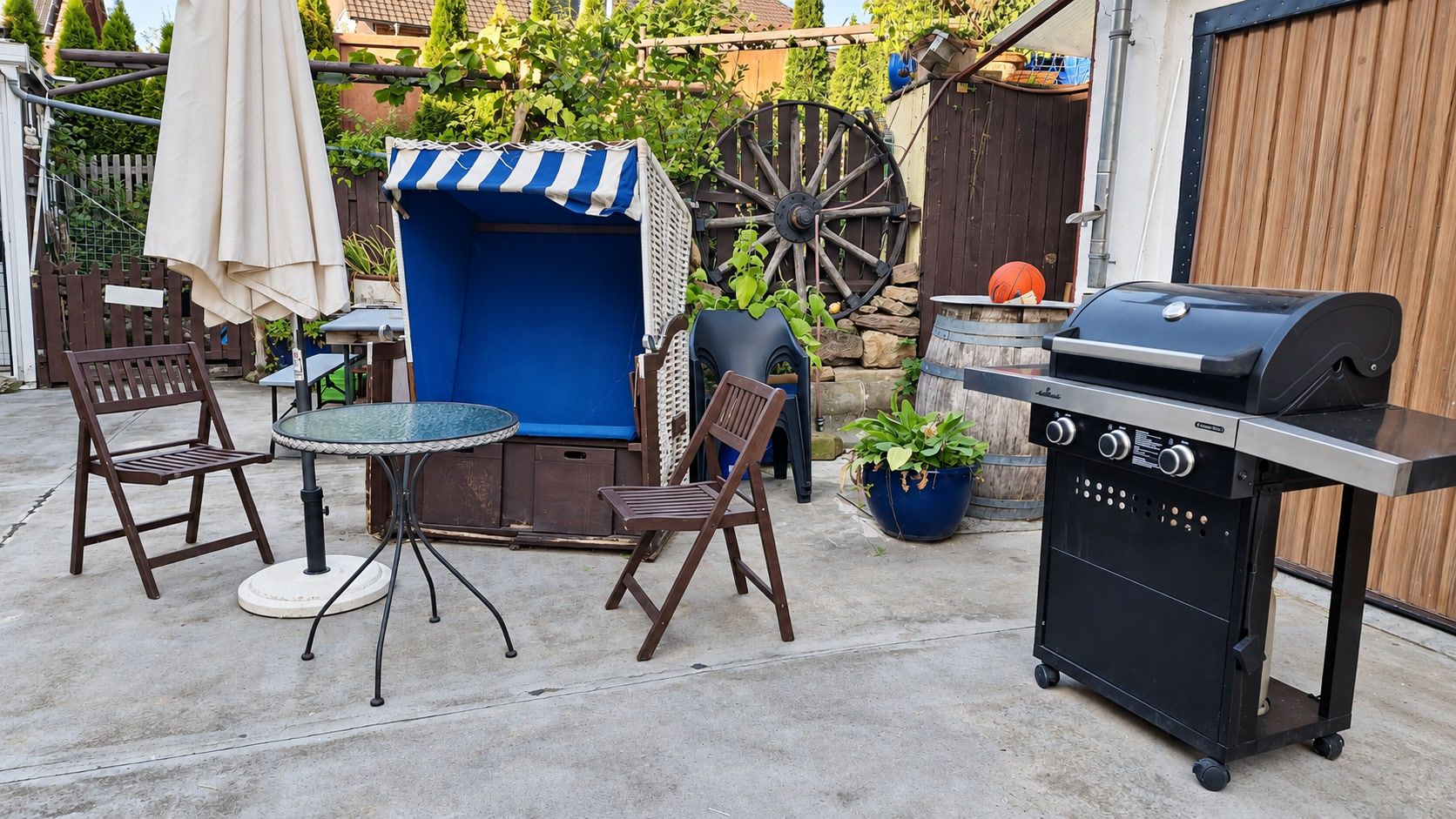 An outdoor patio with a round table, two chairs, a barbecue grill, and a covered seating area.