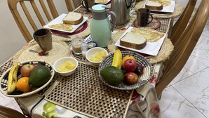 A dining table set with various breakfast items including bread, fruits, and a thermos. - Virunga House (Muhoza)