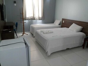Habitació d'hotel amb dos llits, una escriptori amb un ordinador, una cadira i una perxa.